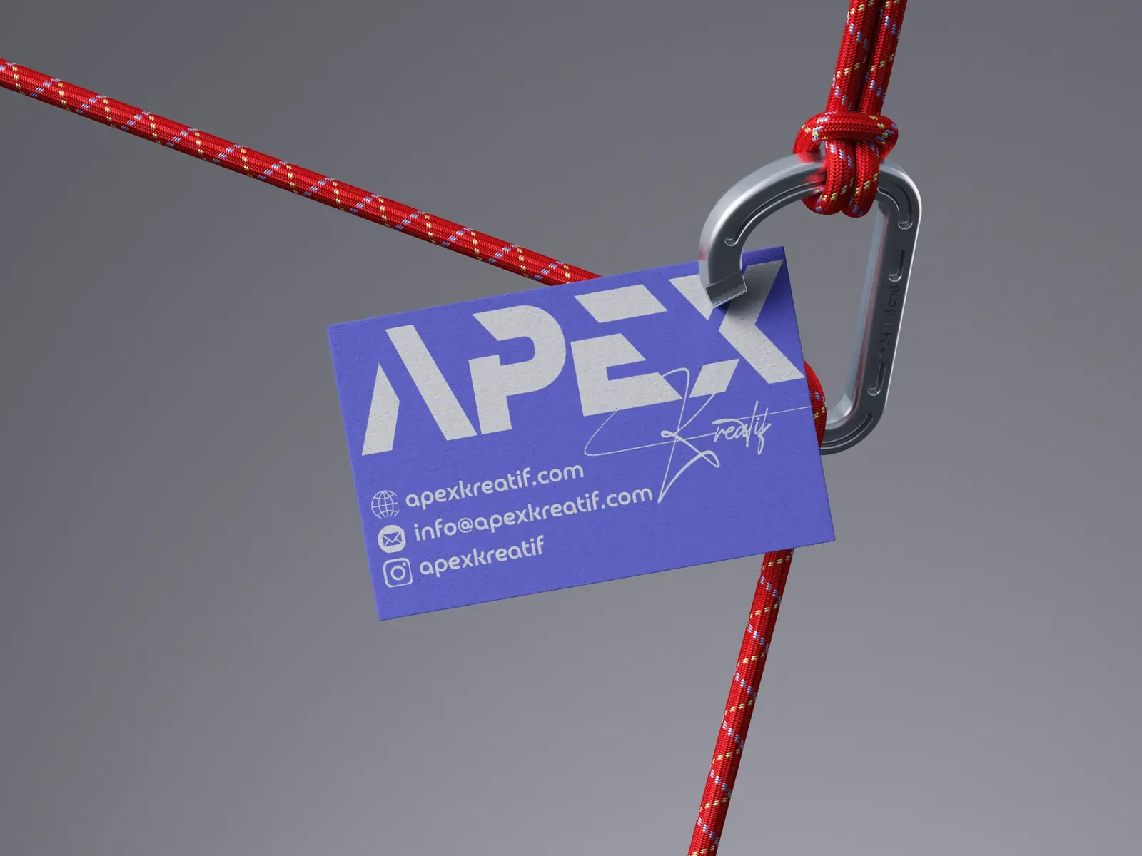 Purple Apex Kreatif business card hanging from a red rope on a carabiner