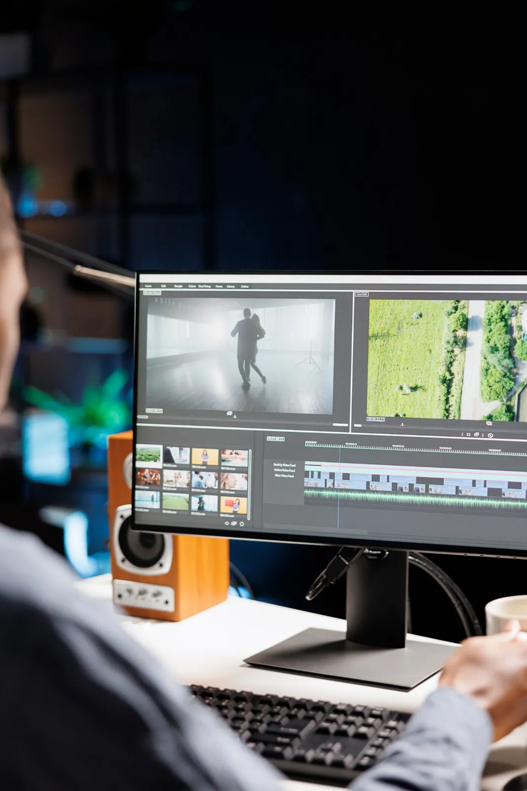 Karanlık bir stüdyoda monitördeki kurgu programında video düzenleyen kurgucu