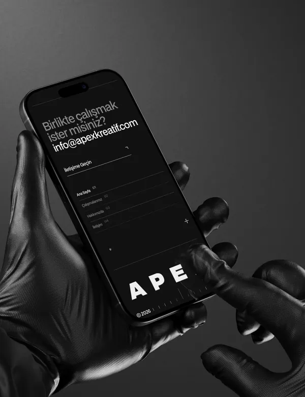 Gloved hands holding a phone with the Apex Kreatif website open